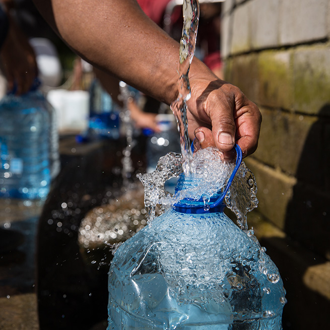 Filling up a jug of water from a faucet.