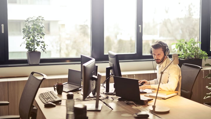 A man typing on a computer in an empty office.