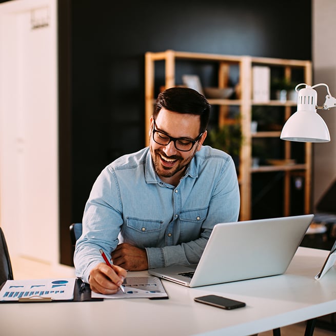 Man in home office writing down notes