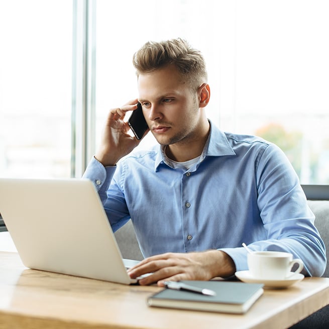 Person on phone in front of laptop