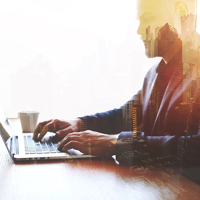 Business man with city overlay on a laptop
