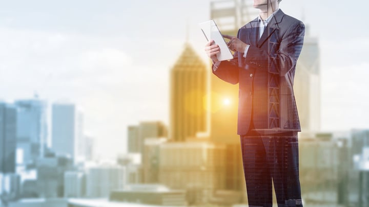 A city backdrop overlaid with a man on an ipad