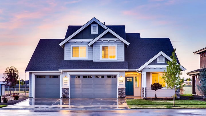 A blue lit-up house with a sunset in the sky