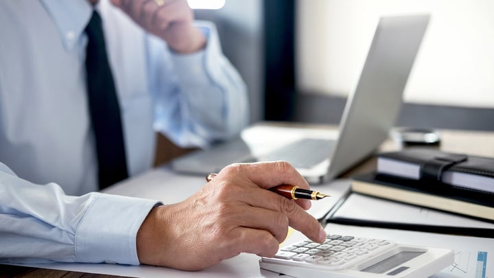 A man sitting at a desk entering numbers into a calculator