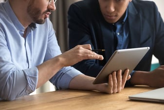 Two men discussing information on an iPad