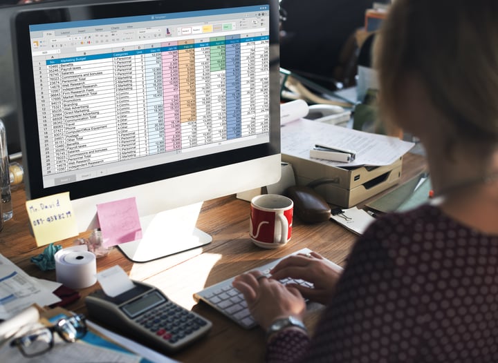 a person entering data into a spreadsheet on a computer