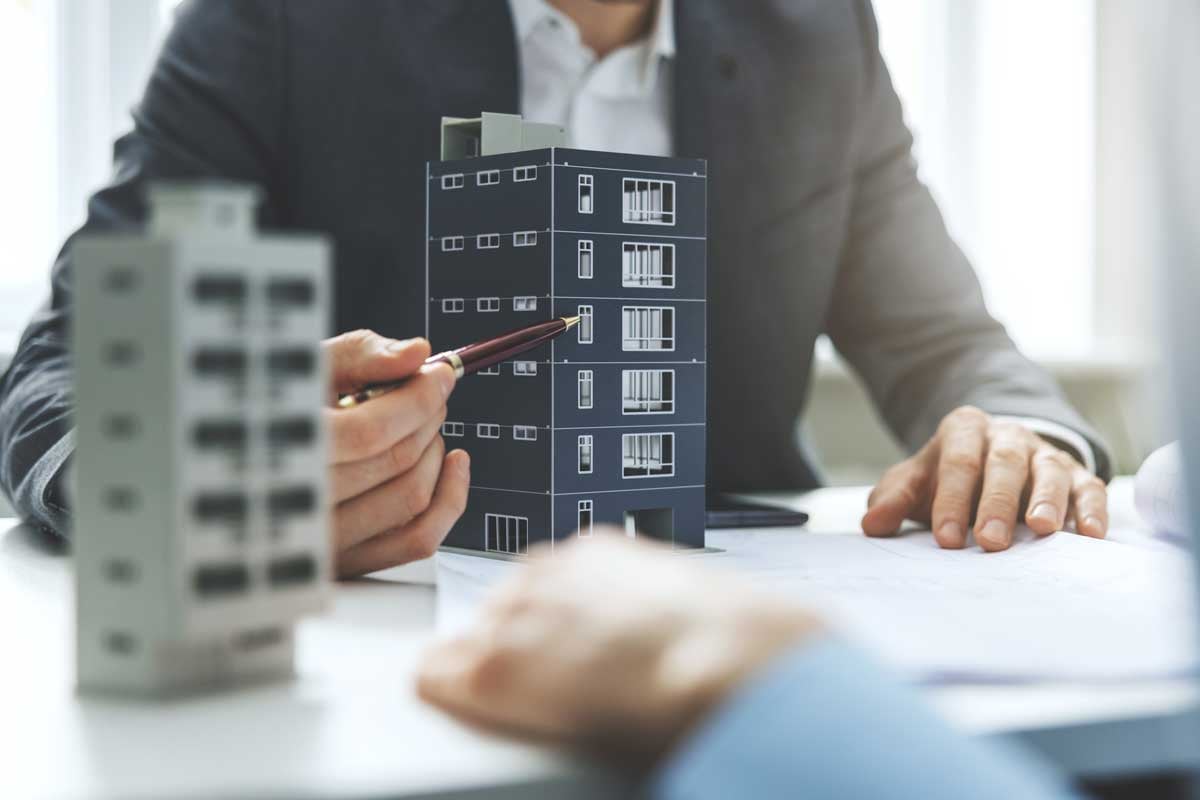man-pointing-pen-to-building